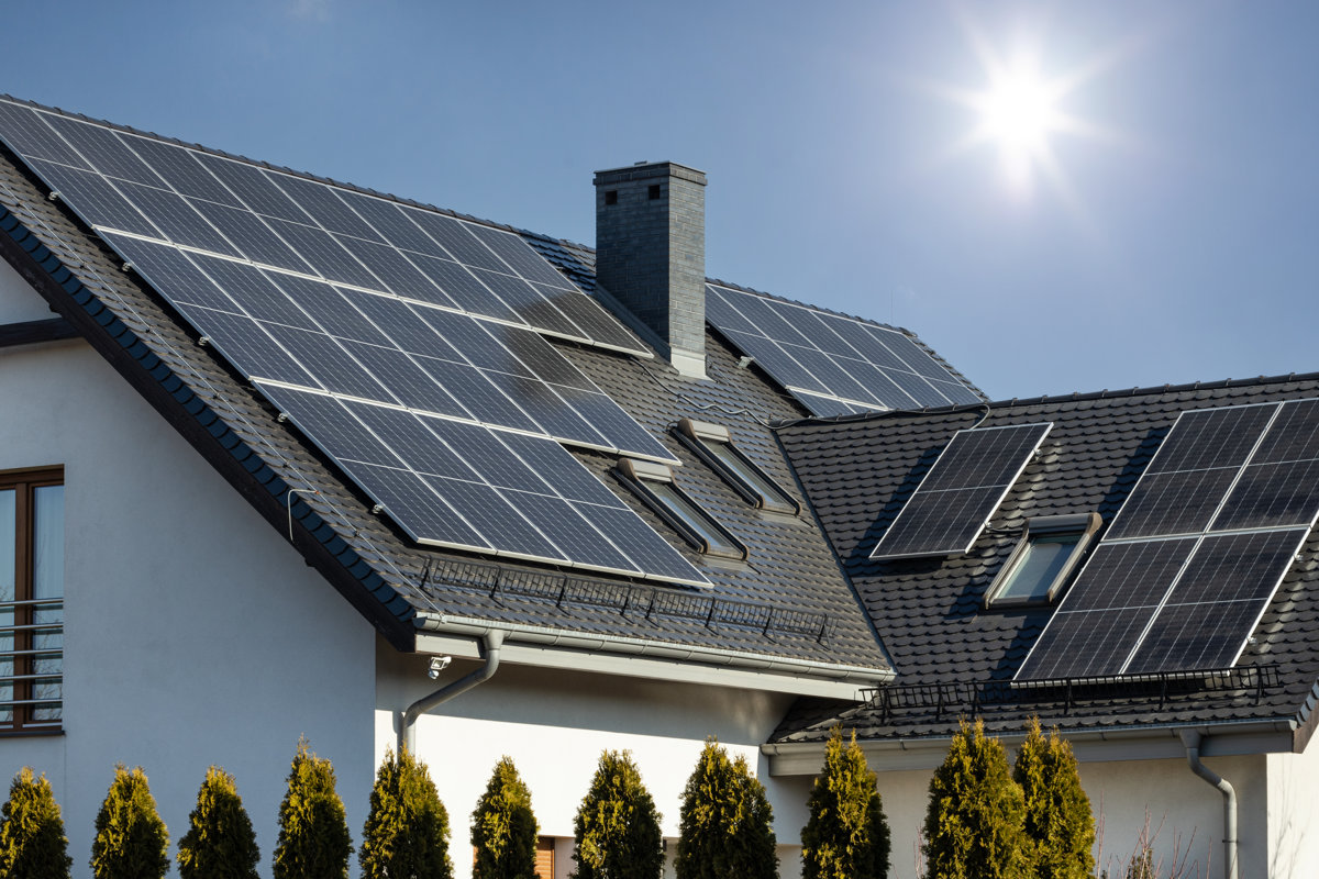 A solar panels on the roof of the house with a blue sky on the background